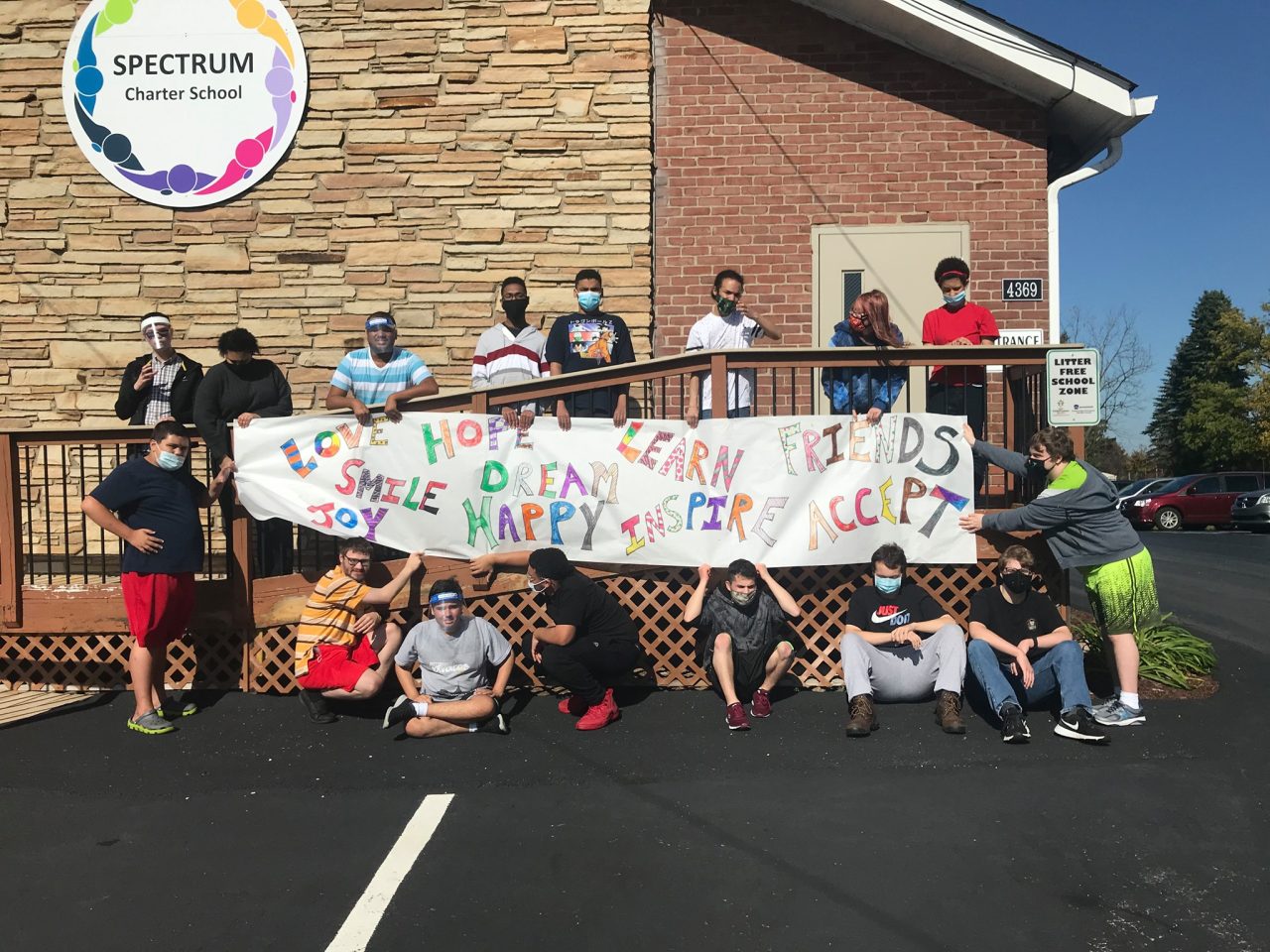 Students and staff holding a handmade banner outside the school