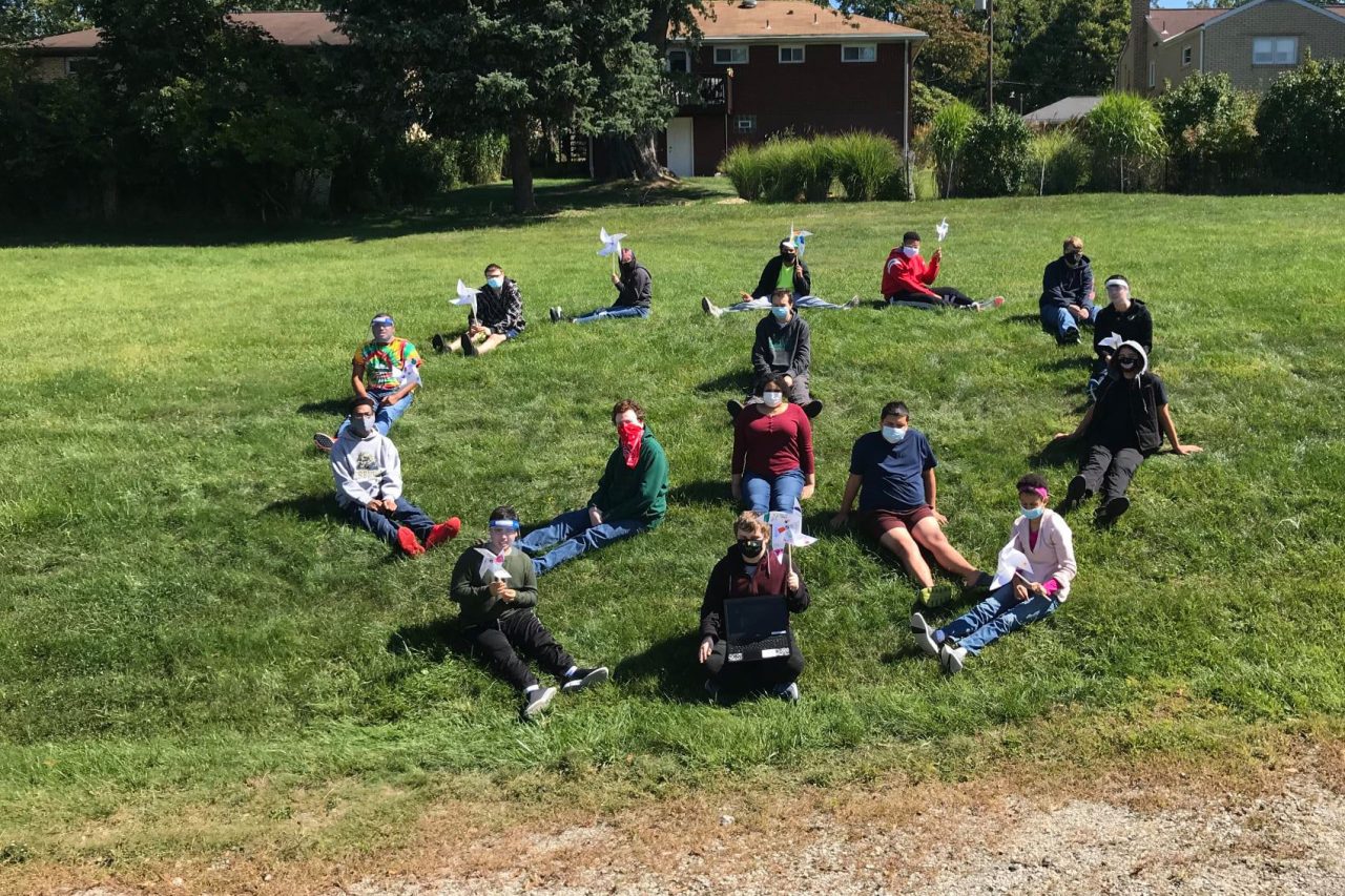 Spectrum students sitting in a large circle on the grass outside the school